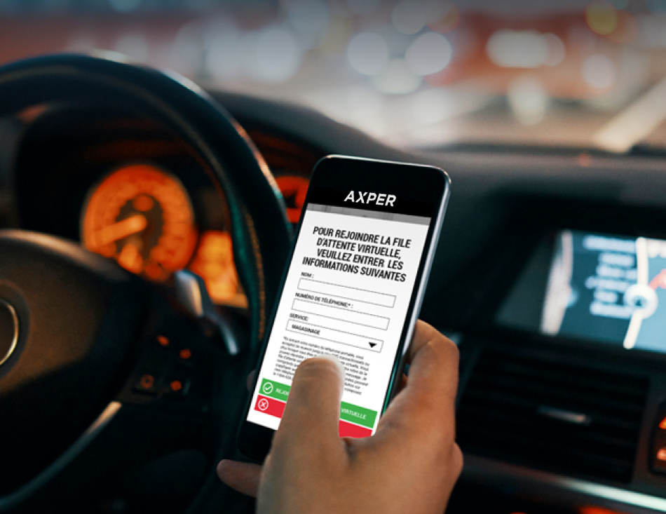 Image d'un téléphone dans une voiture, affichant l'application de file d'attente d'Axper. L'écran affiche "Pour rejoindre la file d'attente virtuelle, veuillez entrer les informations suivantes".